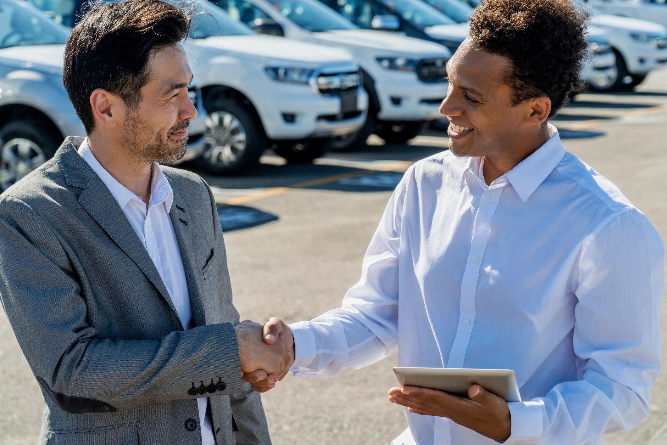 Young car salesman shaking hand with businessman after a sale